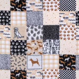 Peut inclure: Une courtepointe en patchwork avec une variété de motifs sur le thème des chiens, y compris des empreintes de pattes, des os et des chiens dans différentes poses. La courtepointe est faite d'un tissu doux et pelucheux, parfait pour se blottir sur le canapé.