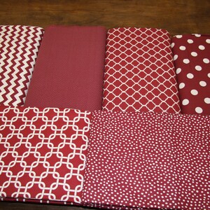 May include: Assortment of fabric pieces in various patterns, including chevron, solid, quatrefoil, and polka dots. The fabrics are primarily burgundy with white accents, suitable for crafting or home decor projects.