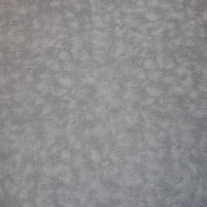 May include: A close-up of a fabric with a mottled texture. The colour is a muted grey, with lighter patches of almost white scattered across the surface. The overall effect is a soft, cloudy pattern.