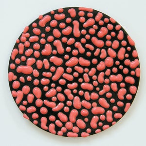 May include: A round black plate with a pattern of pink raised dots and squiggles.