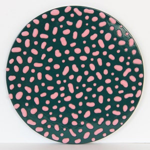 May include: A round, green plate with a pink and white polka dot pattern.