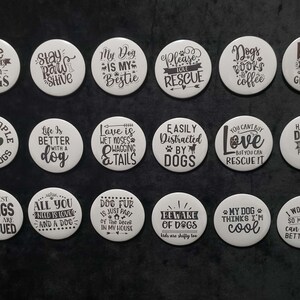 May include: A collection of white round buttons with black text. The buttons feature dog-themed phrases like "Life is better with dogs" and "My dog is my bestie." Ideal for dog lovers.