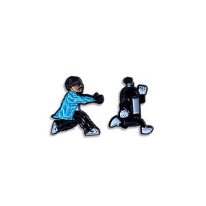 Può includere: Due spille smaltate con personaggi dei cartoni animati. Una raffigura una figura con giacca blu e pantaloni neri, in corsa. L'altra mostra una figura nera con guanti e scarpe bianche, anch'essa in corsa. Entrambe le spille hanno uno sfondo bianco.