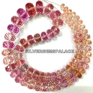 Può includere: Fili di perline di pietre preziose sfaccettate nei toni del rosa e del pesca. Le perline sono infilate insieme, mostrando una sfumatura di colori dal rosa intenso al pesca chiaro. Il testo "SILVERGEMSPALACE" è visibile.