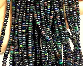 May include: A strand of black opal beads, with iridescent flashes of green, blue, and red. The beads are round and have a smooth, polished finish.