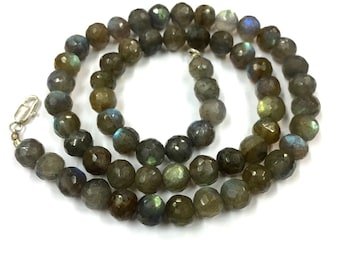 May include: A strand of dark green labradorite gemstone beads with iridescent flashes of blue and gold. The beads are faceted and have a rounded shape. The necklace is approximately 18 inches long.