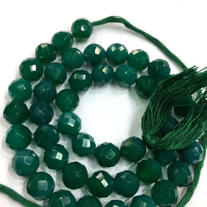 May include: A strand of dark green faceted gemstone beads strung on a green cord with a green tassel.
