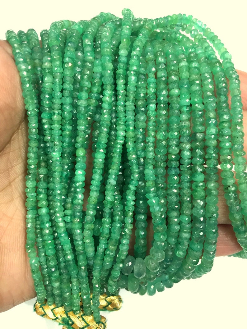 K&ouml;nnte beinhalten: Eine Sammlung von smaragdgr&uuml;nen Edelsteinperlen. Die kleinen, facettierten Perlen sind aufgereiht und bilden mehrere Str&auml;nge. Die Str&auml;nge werden von einer goldenen und gr&uuml;nen Quaste zusammengehalten. Die Edelsteine haben eine lebendige, satte gr&uuml;ne Farbe.