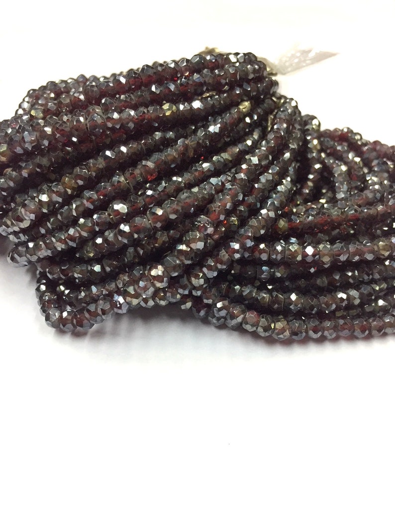 May include: A close-up of a pile of dark red faceted glass beads. The beads are small and have a shiny finish.