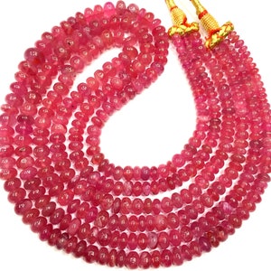 May include: A strand of pink ruby beads, with a smooth, rounded shape. The beads are strung on a cord and are ready to be used for jewellery making.