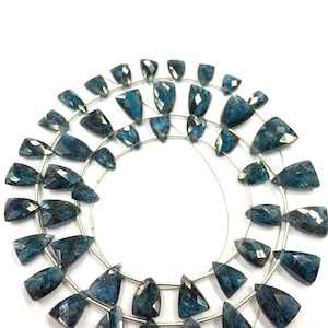 Peut inclure: Un brin de perles de pierres précieuses bleu foncé, chaque perle est facetée et en forme de larme. Les perles sont enfilées sur un fil d'argent et disposées en cercle.
