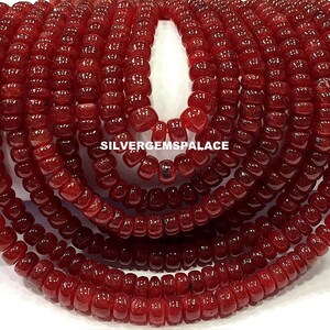 Può includere: Una collana di perline di pietra preziosa rosso scuro. Le perline sono rotonde e hanno un aspetto leggermente sfaccettato. Le perline sono infilate su un filo trasparente e sono pronte per essere utilizzate per la creazione di gioielli.