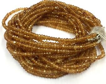 May include: A strand of golden brown gemstone beads. The beads are faceted and have a slightly irregular shape. The strand is coiled and ready to be used for jewelry making.