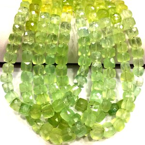 Peut inclure: Un brin de perles de pierres précieuses facettées vert clair. Les perles sont de forme carrée et ont une apparence légèrement translucide.