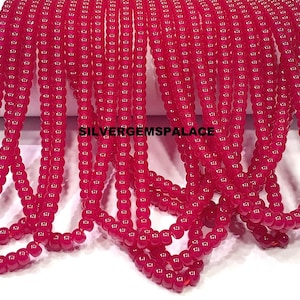 Op de afbeelding: Strengen helderrode, ronde kralen. De kralen zijn aan elkaar geregen, waardoor meerdere lijnen van hetzelfde product ontstaan. De tekst "SILVERGEMSPALACE" is zichtbaar. Deze kralen kunnen worden gebruikt voor het maken van sieraden.