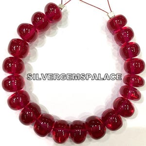 Puede incluir: Una hebra de cuentas de piedras preciosas de color rojo intenso, enhebradas en un hilo de plata. Las cuentas son redondas y lisas, con un acabado brillante. La hebra mide aproximadamente 45 cm de largo y es perfecta para hacer joyas.