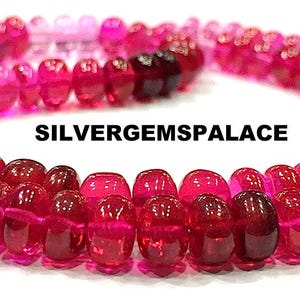 May include: A necklace of graduated, translucent, red and pink beads. The beads transition from light pink to deep red. The text "SILVERGEMSPALACE" is printed in black across the image. The beads are strung together.