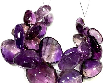Puede incluir: Una hebra de cuentas de piedra preciosa de amatista facetada, cada cuenta es de color morado oscuro con una ligera variación de tono. Las cuentas están enhebradas en un hilo transparente y tienen un acabado anudado.