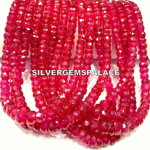 May include: A strand of bright red faceted gemstone beads. The beads are small and round, and they are strung together on a clear thread. The beads are arranged in a loose pile, and they are all the same size and shape. SILVERGEMSPALACE is printed on the beads.
