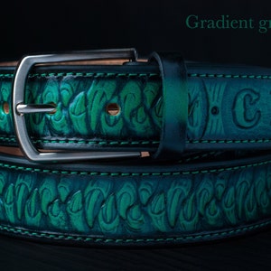 May include: A gradient green belt featuring a textured, embossed pattern of repeating claw-like shapes, a silver-toned metal buckle, and green stitching. The belt includes the embossed letters CX on the strap and the text Gradient green.