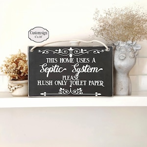 Può includere: Un cartello rettangolare in legno nero con testo bianco e decorazioni. Il cartello recita: "QUESTA CASA UTILIZZA UN sistema settico, SI PREGA DI SCARICARE SOLO CARTA IGIENICA". Un cartello più piccolo sopra recita "Custom sign 6" x 10" (15,24 cm x 25,4 cm).