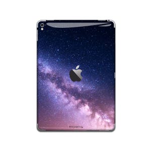 May include: An iPad case featuring a galaxy design with a dark blue background and a swirling pink and purple nebula. The Apple logo is visible in the centre of the case.