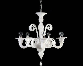 May include: White glass chandelier with five lights and a decorative, ornate design. The chandelier has a white, frosted glass finish and a chain hanging from the ceiling.