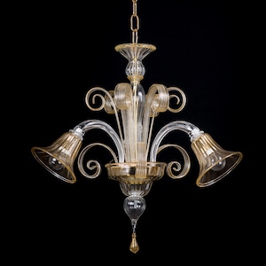 Puede incluir: Una lámpara de araña de cristal transparente y dorado con tres luces. La lámpara tiene un diseño tradicional con un tallo central y tres brazos curvos. Cada brazo tiene una pantalla de cristal en forma de campana.