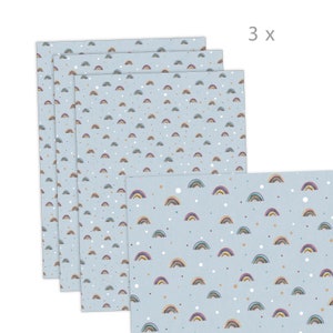 Könnte beinhalten: Vier hellblaue Papierbögen mit einem sich wiederholenden Muster aus kleinen, bunten Regenbogen und weißen Punkten. Der Text "3 x" befindet sich oben rechts. Die Regenbogen haben einen Aquarell-Effekt.
