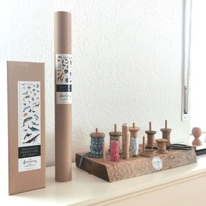 May include: A set of wooden spools with colorful string, a brown cardboard tube with a poster inside, and a brown cardboard box with a poster of sea creatures. The poster on the box is titled "Messeiste Meeres Tiere 29.7x84.2cm" and the poster in the tube is titled "Zooti Soxto".