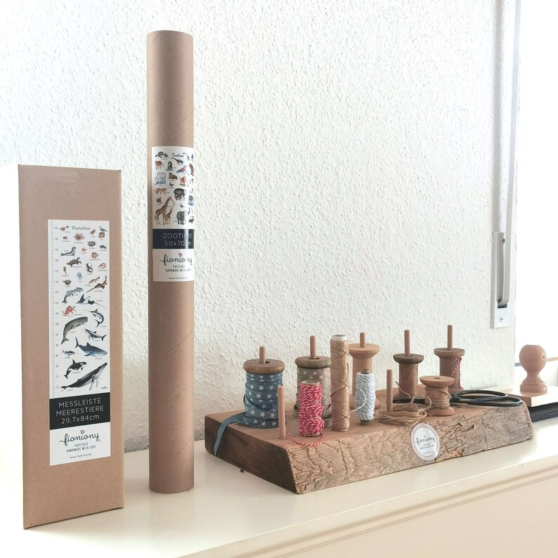 May include: A set of wooden spools with colorful string, a brown cardboard tube with a poster inside, and a brown cardboard box with a poster of sea creatures. The poster on the box is titled "Messeiste Meeres Tiere 29.7x84.2cm" and the poster in the tube is titled "Zooti Soxto".