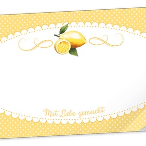 Può includere: Un adesivo giallo e bianco con un design a limone e il testo "Mit Liebe gemacht". L'adesivo ha uno sfondo a pois e un bordo a festoni.