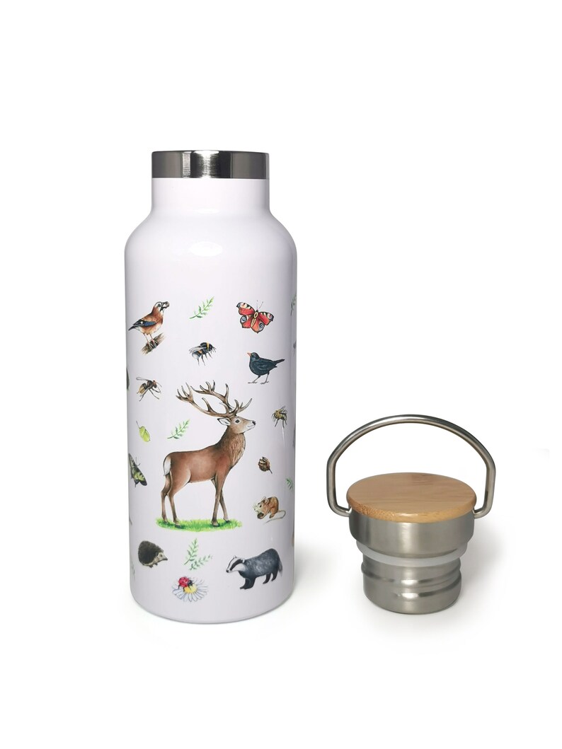 May include: White stainless steel water bottle with a woodland animal print design. The bottle has a bamboo lid with a stainless steel ring and a carrying handle.