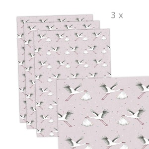 K&ouml;nnte beinhalten: Drei Bl&auml;tter rosa Geschenkpapier mit einem wei&szlig;en Storchenmuster, das ein Babyb&uuml;ndel tr&auml;gt. Das Papier hat ein dezentes wei&szlig;es Punkte-Muster.