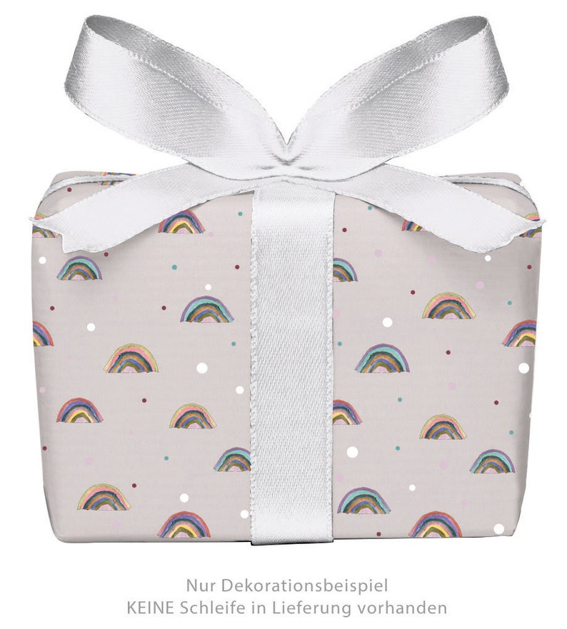 May include: A gift box wrapped in light pink wrapping paper with a rainbow pattern and white polka dots. The box is tied with a white satin ribbon. The text on the box reads "Nur Dekorationsbeispiel KEINE Schleife in Lieferung vorhanden".