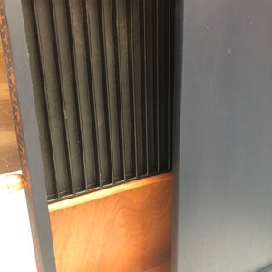 Puede incluir: Un armario azul oscuro con un caj&oacute;n de madera que tiene un divisor de metal negro en el interior. El caj&oacute;n est&aacute; abierto y el divisor es visible.
