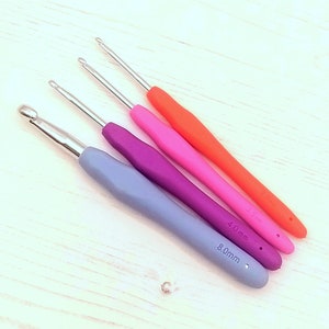 May include: Four crochet hooks in different sizes and colors. The hooks are 3.5mm, 4.0mm, and 8.0mm. The hooks are orange, pink, purple, and blue.