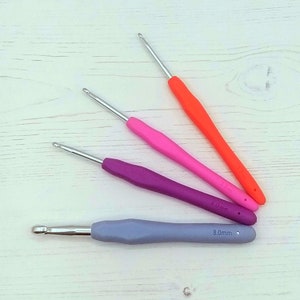 May include: Four crochet hooks in different colors and sizes. The hooks are orange, pink, purple, and gray. The sizes are 3.5 mm, 4.0 mm, and 8.0 mm.