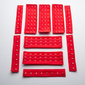 Hysk- och hakknäppning, 8 rader, 5 par (5 set) 15 cm höjd, 5 cm bredd, isyningsbar röd färg, underklädestillbehör.
