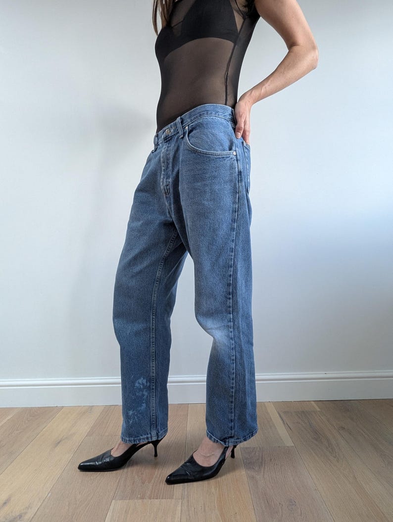Op de afbeelding: Lichtblauwe jeans met een relaxte pasvorm. De jeans hebben een klassiek ontwerp met vijf zakken en een knoop- en ritssluiting. De jeans worden gecombineerd met zwarte pumps met spitse neus.