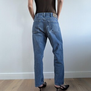 Op de afbeelding: Lichtblauwe denim jeans met een rechte pijp. De jeans hebben een klassiek vijf-zakken ontwerp en een vervaagde wassing. Het model draagt zwarte hakken. De jeans zijn een casual, alledaags kledingstuk.