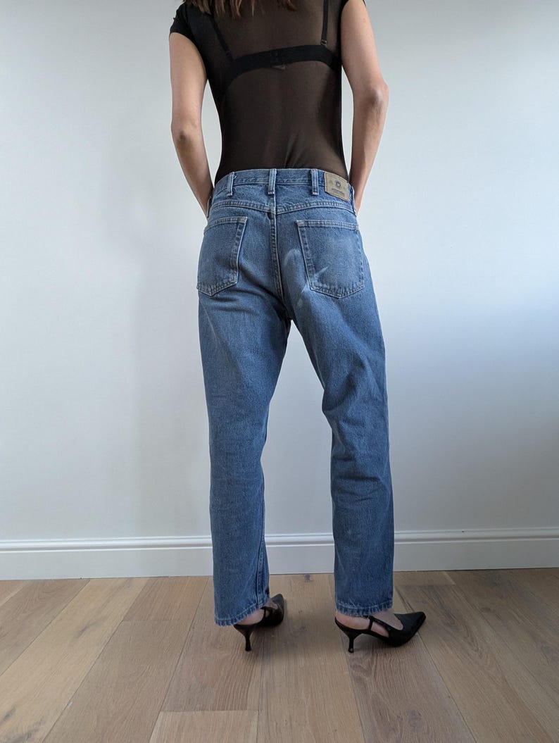 Op de afbeelding: Lichtblauwe denim jeans met een rechte pijp. De jeans hebben een klassiek vijf-zakken ontwerp en een vervaagde wassing. Het model draagt zwarte hakken. De jeans zijn een casual, alledaags kledingstuk.