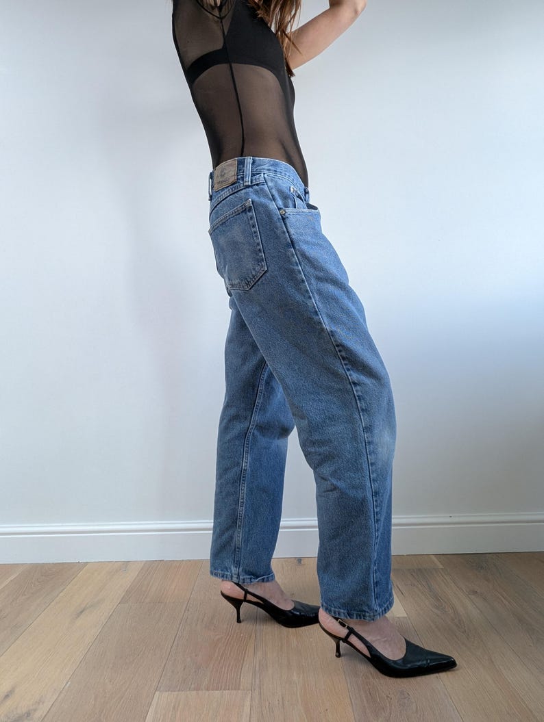 Op de afbeelding: Lichtblauwe denim jeans met een klassieke rechte pijp. De jeans heeft een vervaagde wassing en een traditioneel ontwerp met vijf zakken. Het model draagt zwarte slingback hakken.