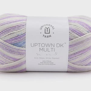 May include: A skein of variegated yarn featuring a color palette of white, lavender, and light blue. A white paper label wraps around the center, displaying the text Universal Yarn, Uptown DK Multi, and the phrase Knit, Relax, Smile, Repeat.