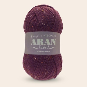May include: A ball of purple yarn with flecks of white and orange. The yarn is labeled "Hayfield Bonus Aran Tweed 28% Wool Blend."