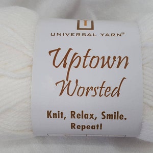 May include: A skein of white yarn labeled "Uptown Worsted" by Universal Yarn. The label also says "Knit, Relax, Smile. Repeat!"