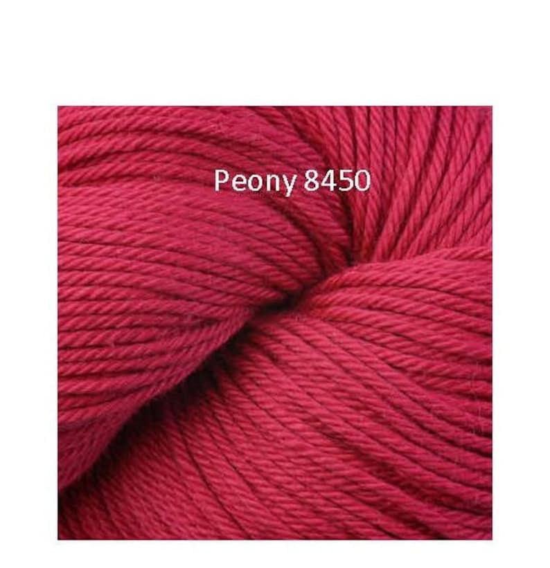 May include: A close-up of a skein of deep red yarn. The yarn is soft and fluffy, and it is perfect for knitting or crocheting. The label on the yarn reads "Peony 8450".