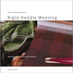 Peut inclure: Le livre "The Ashford Book of Rigid Heddle Weaving", édition révisée, par Rowena Hart. La couverture du livre présente un gros plan d'un tissu tissé rouge et vert sur un métier à tisser à lisses rigides.