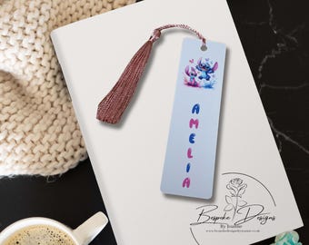 May include: A blue and pink bookmark with a cartoon Stitch character and the name Amelia printed in colorful letters. The bookmark has a pink tassel.