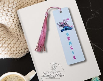 May include: A blue and pink bookmark with a cartoon image of Stitch and Angel from the Disney movie Lilo & Stitch. The bookmark has a pink tassel and the name "Gracie" written in pink and blue letters.